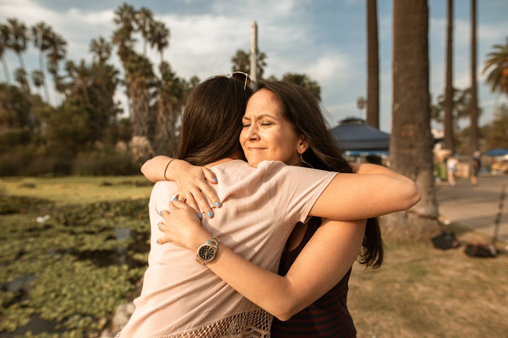 Two women hugging outdoors near a lake, conveying love and friendship because that connection is important to rewire your brain